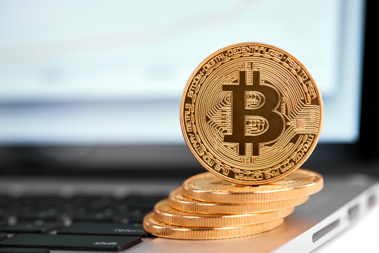 Stack of Bitcoins on top of a laptop. Bitcoin, Ether prices rise, Polygon leads top 10 in gains, Doge, Shib retreat