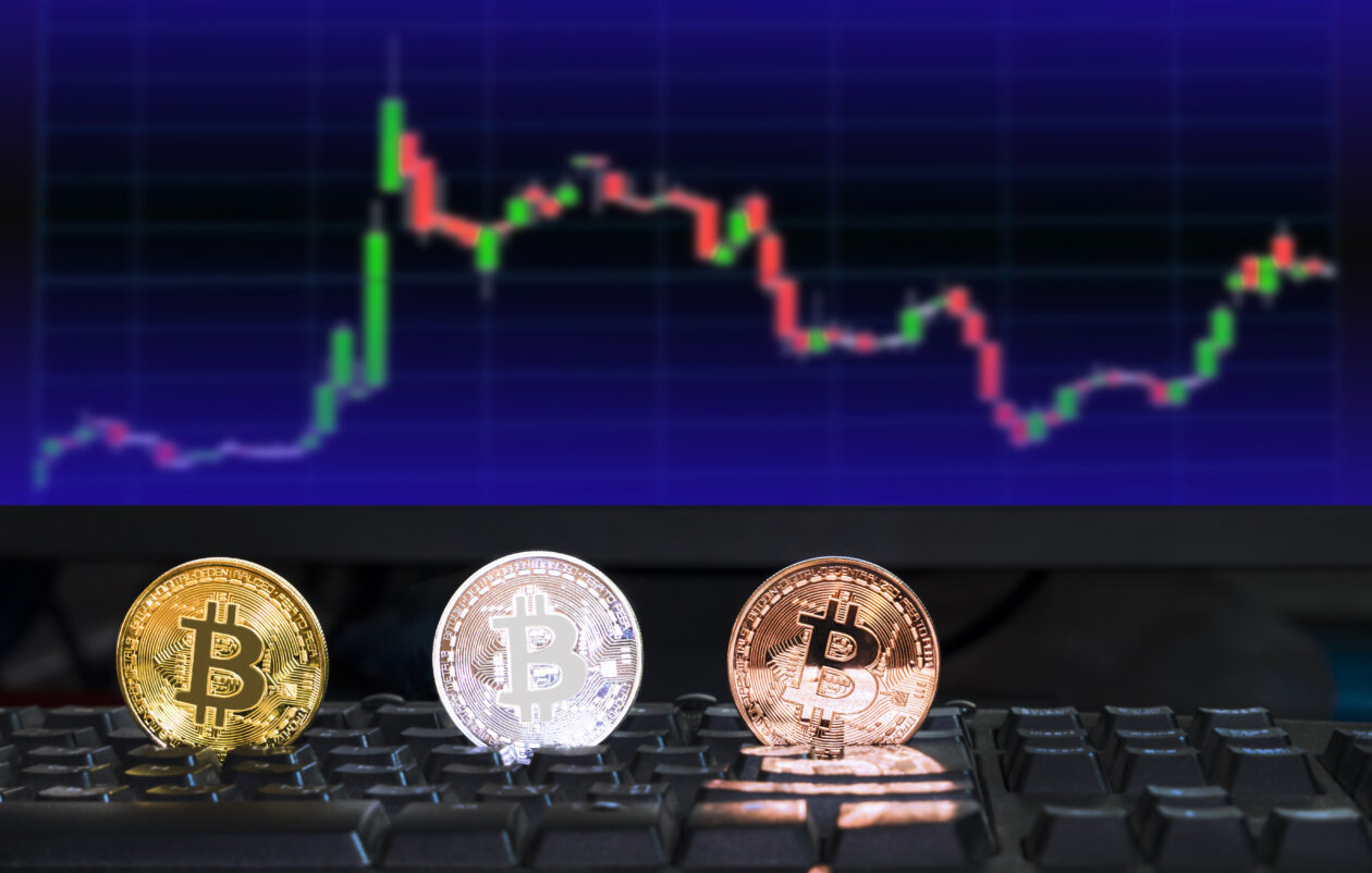 Bitcoin, Ether in red, XRP lone gainer in top 10 9 3 different colored bitcoin digital currency on computer keyboard with blurred background of investing chart stock market trading in monitor, future financial currency concept